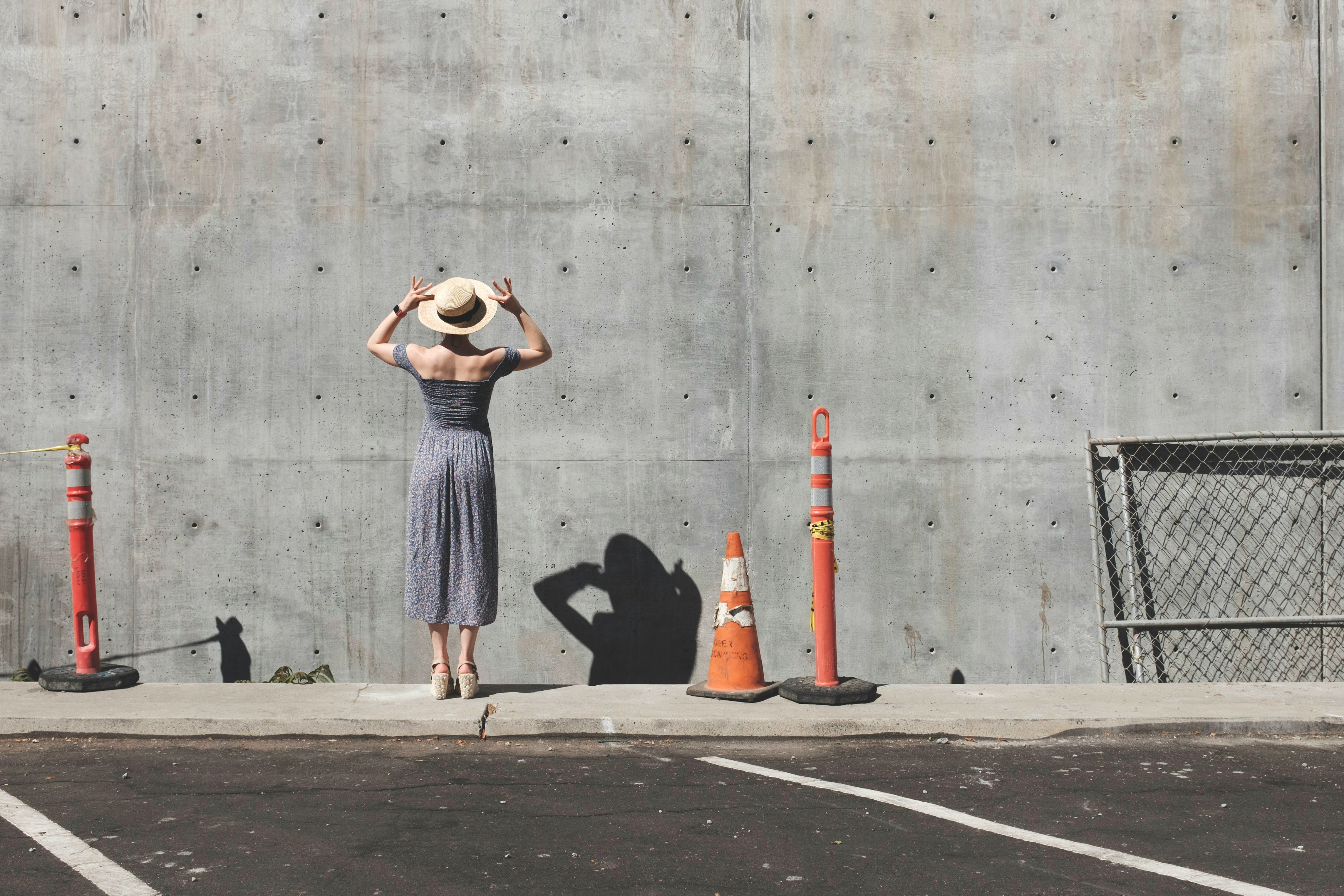 woman in gray dress facing a wall